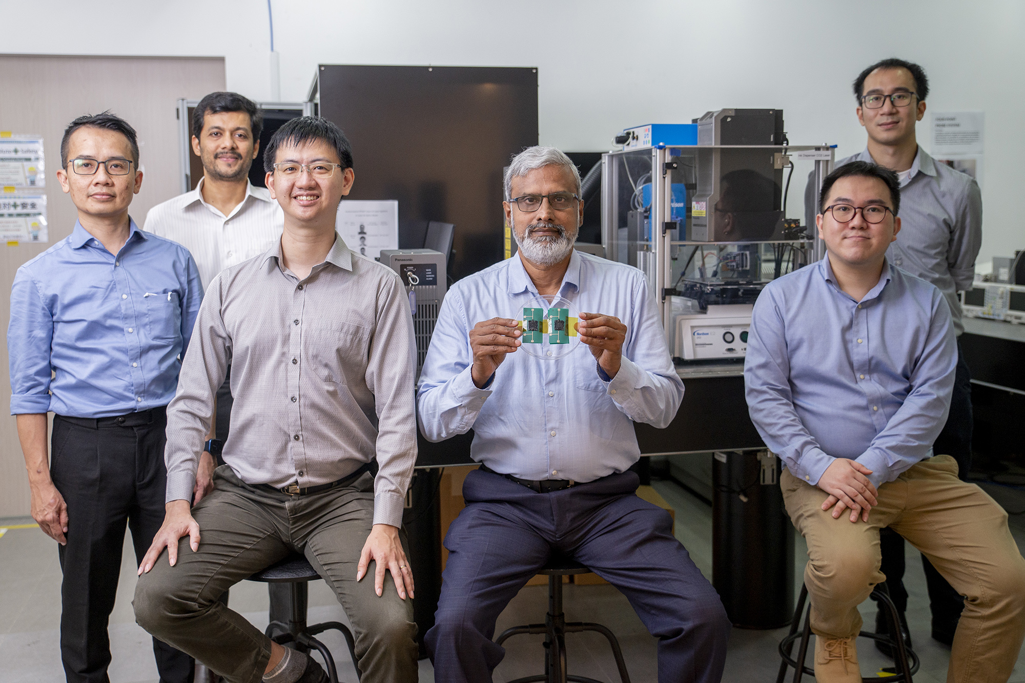 Multi-material printer team includes (from left) Dr. Low Mun Ji, general manager, Panasonic; Dr. Suchand Sandeep, research fellow, NTU School of Mechanical and Aerospace Engineering (MAE); Dr. Nicholas Tham, senior research engineer, Panasonic; Co-leader and associate professor Murukeshan Vadakke Matham, NTU School of MAE, Singapore Centre for 3D Printing; Dr. Joel Lim, research engineer, Panasonic, and Daryl Lim, research associate, NTU School of MAE. Murukeshan holds a sample of a 3D-printed stretchable pressure sensor. 