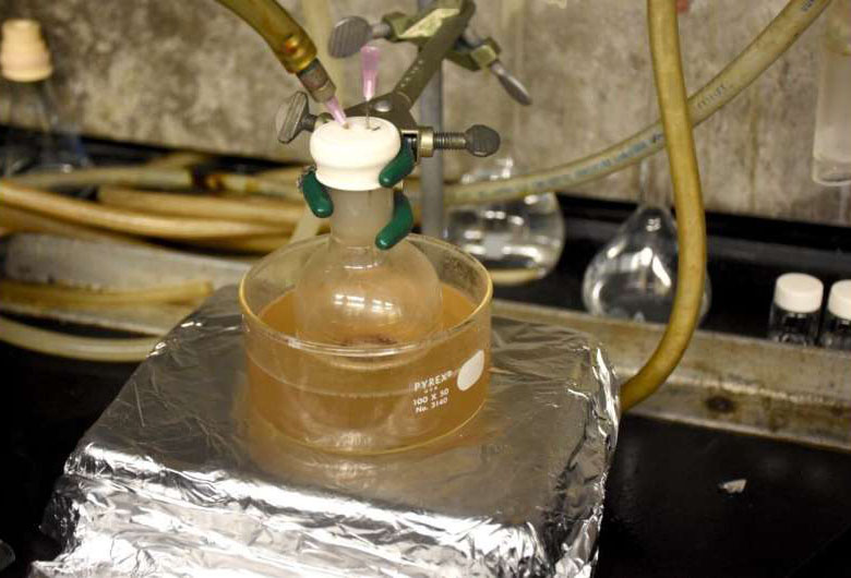A flask filled with waxes from waste PE and PP is heated in an oil bath and oxidized by airflow to produce fatty waxes via catalytic oxidation. 