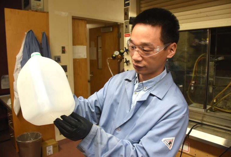It’s not an HDPE water jug, it’s a bar of soap. Dr. Guoliang Liu inspects a container whose molecules he will convert to fatty wax for use in soap.