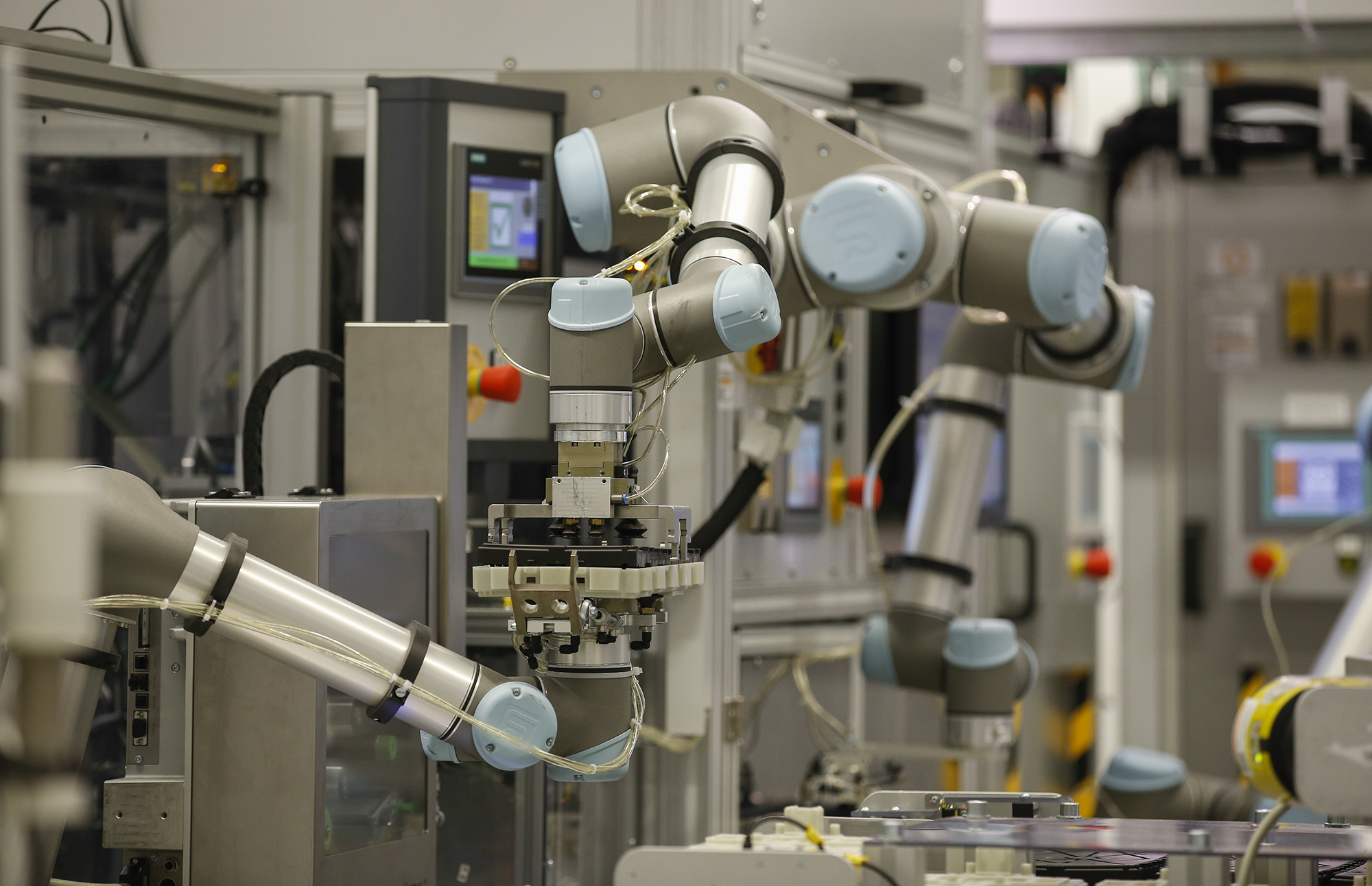 Cobots work with automotive electronics in a Continental work cell.  