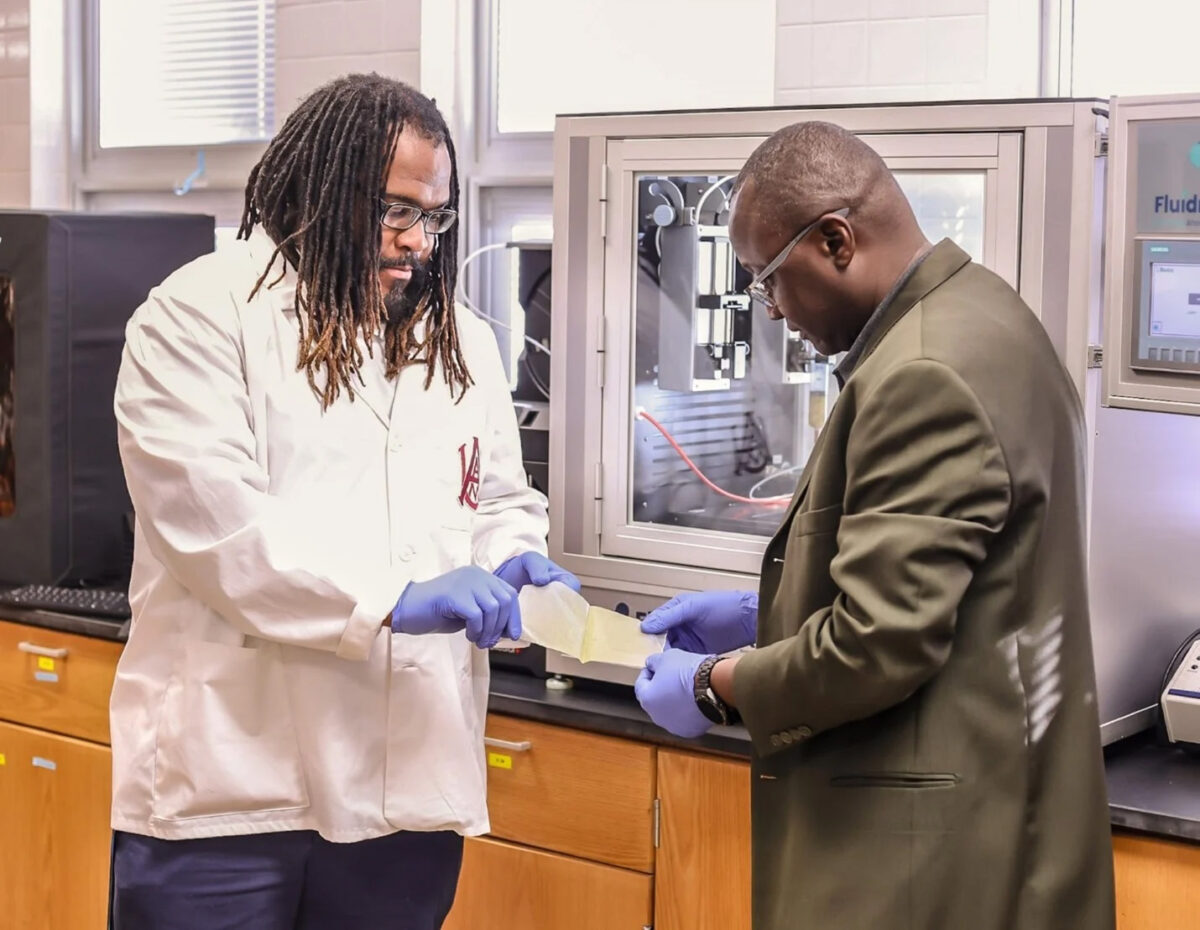 Aaron Dudley (left) and Lamin Kassama hold a sample of the film packaging material.