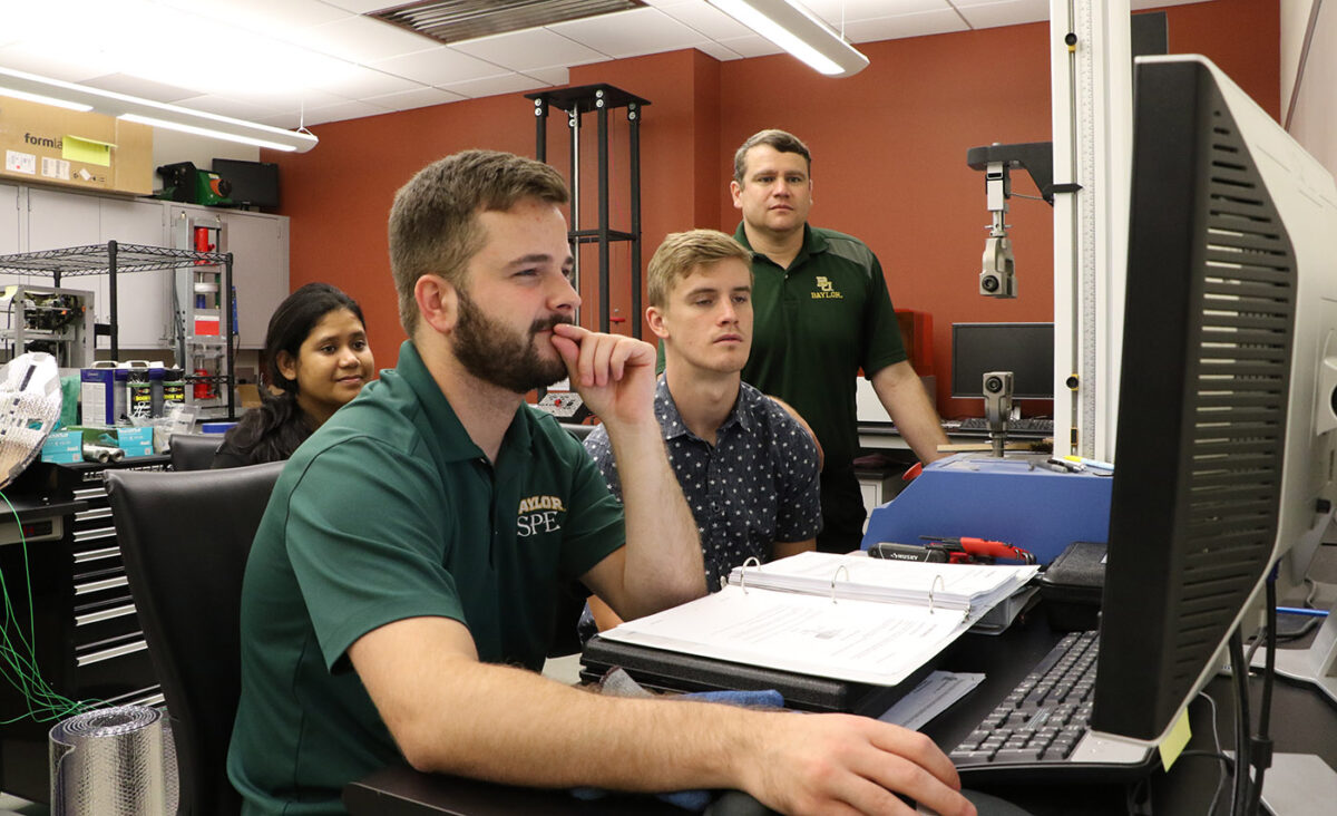 Timothy Russell, Baylor SPE student president, demonstrates how to use a drop tower for impact testing with students Rifat Nargis (left) and Derryck Peters (right) and faculty advisor David Jack (standing).