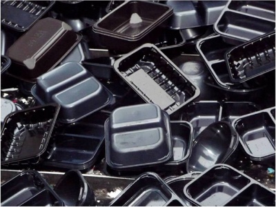 Black plastic packaging on a sorting line showing why carbon black pigments evade NIR detection. Courtesy of The WRAP report Recyclability of Black Plastics: An Overview synthesizes