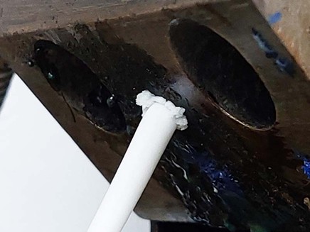 Localized polymer buildup at a metal interface. Surface condition and geometric transitions promote material hang-up and deposit formation in PFAS-free extrusion systems. Courtesy of Radical.