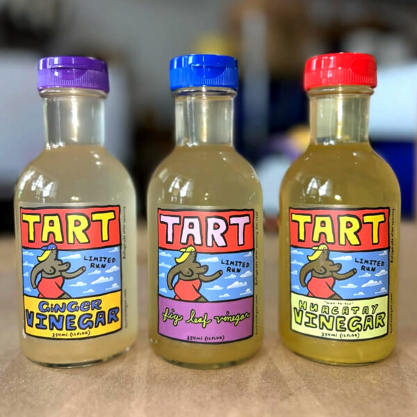 Vinegar bottle labels execute artisanal positioning through vibrant illustrative maximalism: whimsical cartoon-style drawings evoke nostalgic hand-drawn animation cells, bold blocky typography provides structural counterpoint to organic illustration work, and saturated color palette creates emotional resonance that transcends clinical digital rendering. Design by Rob Moss Wilson.