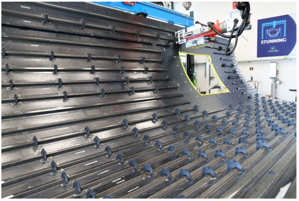 The lower shell of the MFFD demonstrator after welding the clips to the skin and stringer. Courtesy of Robotic Sequential Ultrasonic Welding of Thermoplastic Composites: From Coupons to a Full-Scale Fuselage Demonstrator.